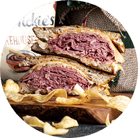 Sandwich filled with corned beef, grilled sauerkraut, Swiss cheese, and 1000 Island dressing on grilled Rye. Cut in half and stacked on one another.