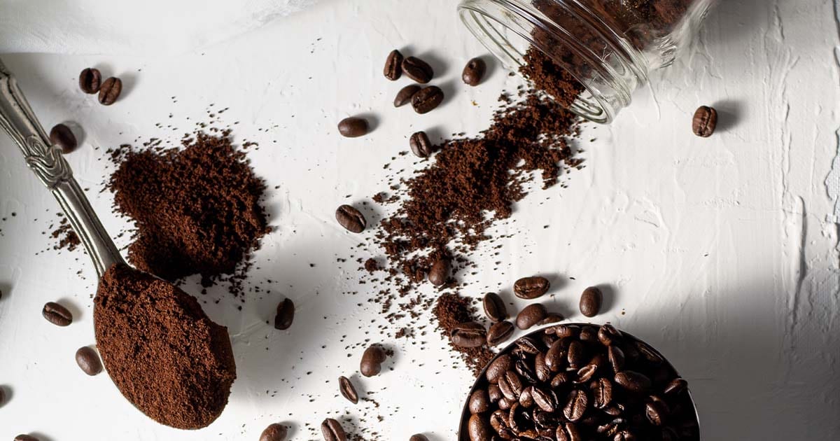 Coffee grounds and coffee beans with spoon and jar